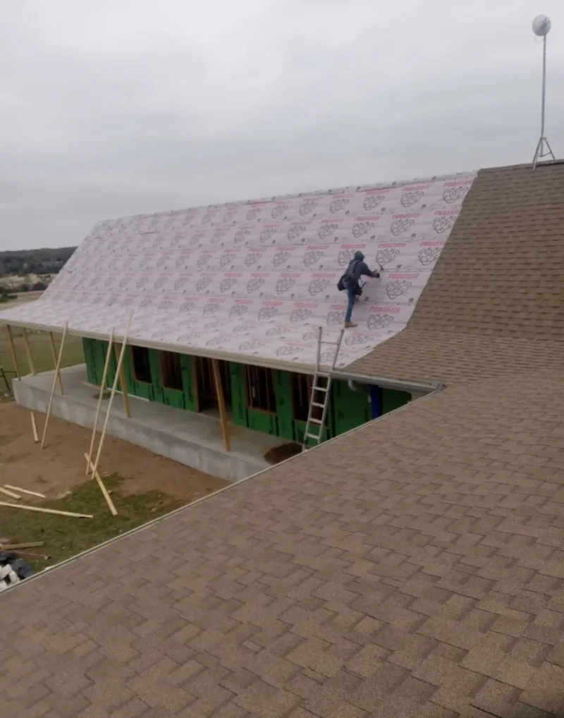 Worker preparing underlayment for a metal roof installation in Linton